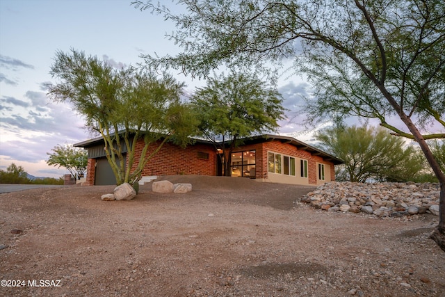 back house at dusk featuring a garage