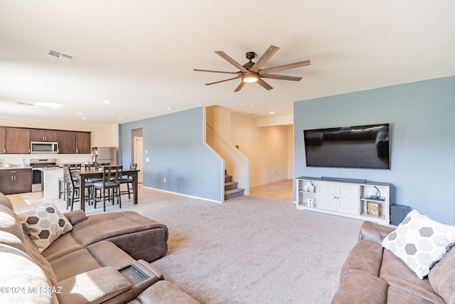 carpeted living room with ceiling fan