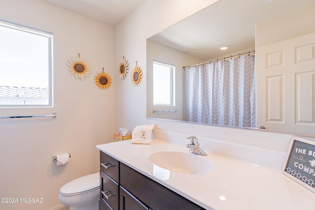 bathroom featuring vanity, walk in shower, and toilet