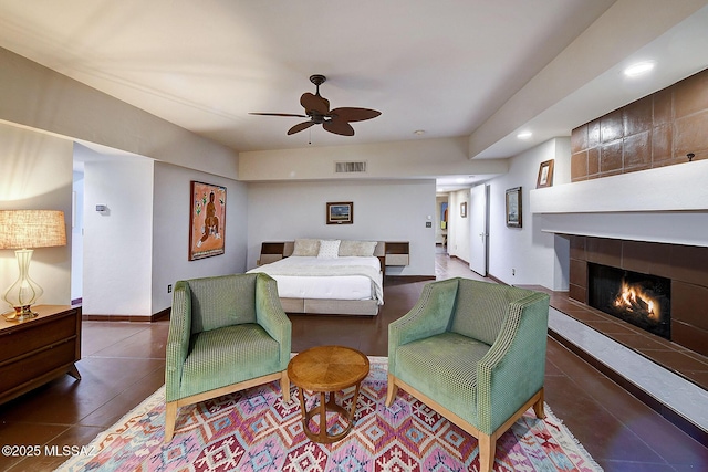 bedroom featuring ceiling fan and a tile fireplace