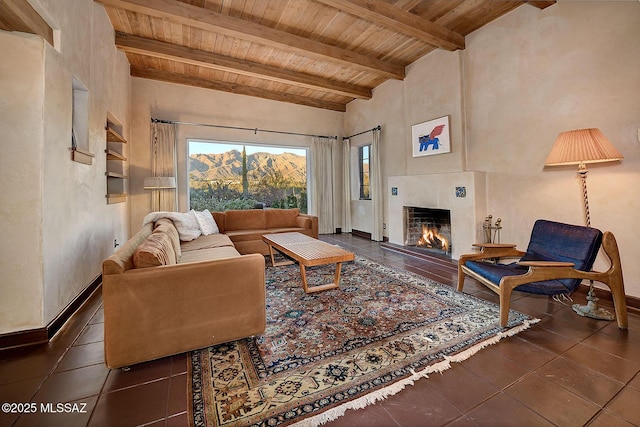 living room featuring wood ceiling, a tile fireplace, beam ceiling, dark tile patterned flooring, and a mountain view