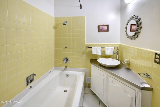 bathroom with tile patterned floors, vanity, tile walls, and tiled shower / bath