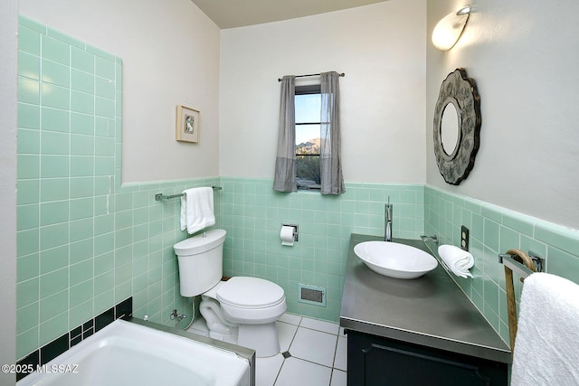 bathroom featuring a tub, tile patterned floors, toilet, vanity, and tile walls