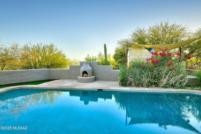 view of pool featuring exterior fireplace