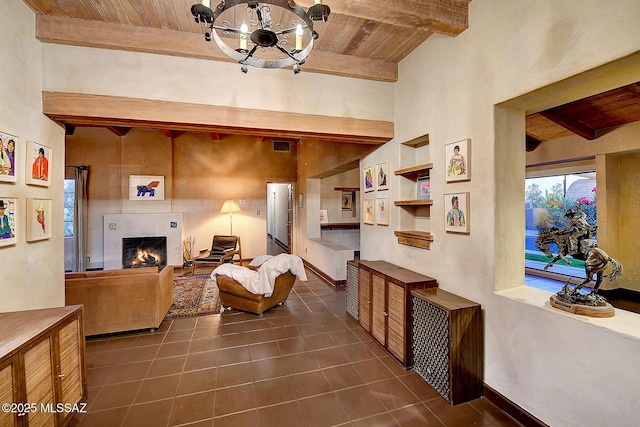 tiled living room featuring built in features, beamed ceiling, wood ceiling, and a notable chandelier