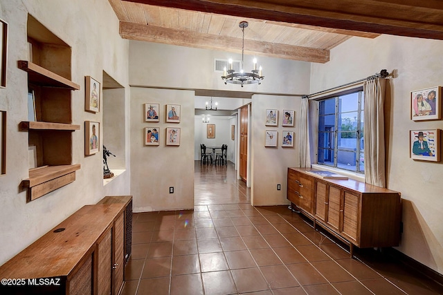 hall featuring beam ceiling, an inviting chandelier, dark tile patterned flooring, and wooden ceiling