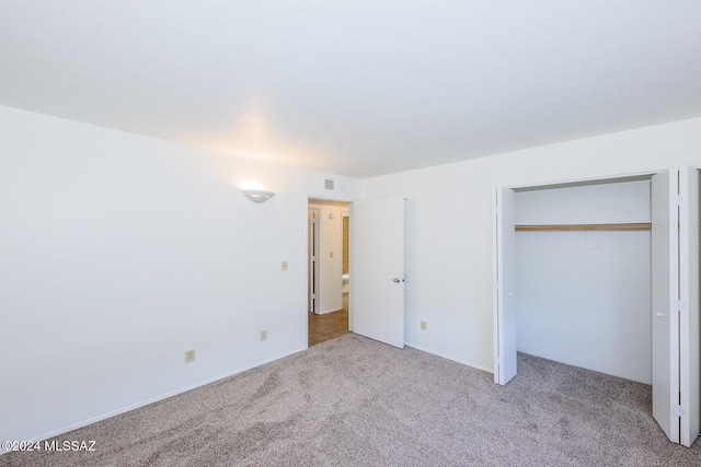 unfurnished bedroom featuring light colored carpet and a closet