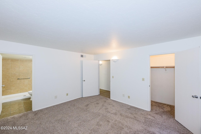 unfurnished bedroom with carpet floors, a closet, ensuite bath, and a walk in closet