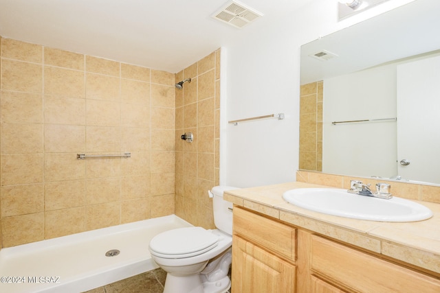 bathroom featuring tiled shower, vanity, toilet, and tile patterned flooring