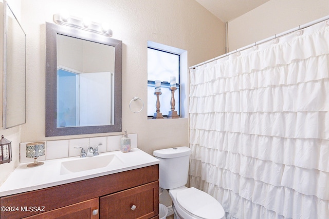 bathroom with curtained shower, vanity, and toilet