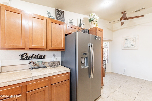 kitchen featuring stainless steel refrigerator with ice dispenser, ceiling fan, tile countertops, and light tile patterned flooring