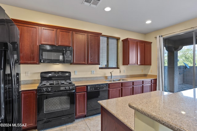 kitchen with light tile patterned floors, sink, black appliances, and light stone counters