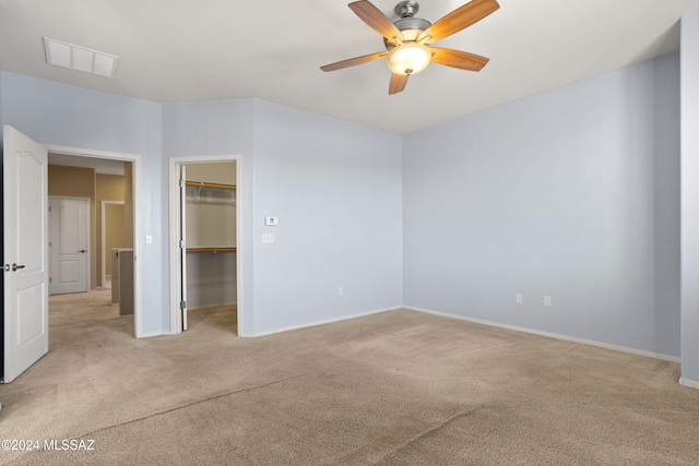 unfurnished bedroom featuring a spacious closet, ceiling fan, light colored carpet, and a closet