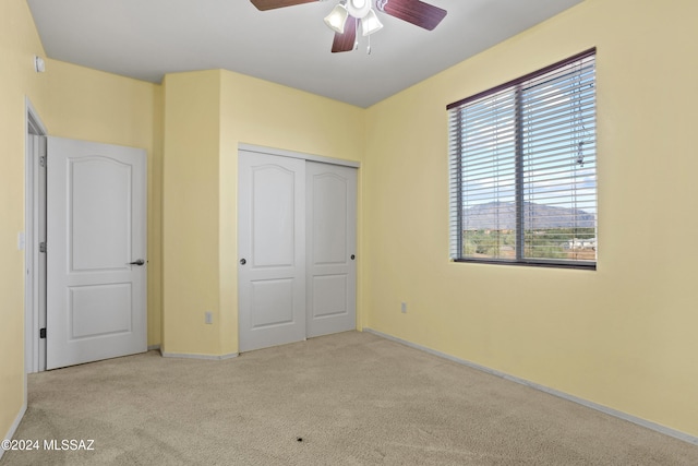 unfurnished bedroom with light carpet, ceiling fan, and a closet