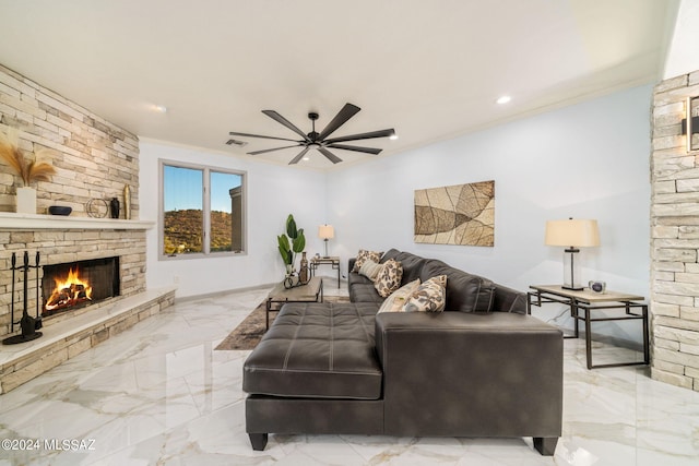 living room with ornamental molding, ceiling fan, and a stone fireplace