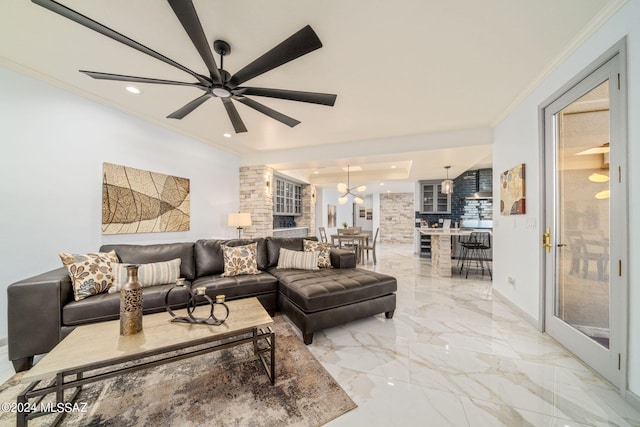 living room featuring ceiling fan with notable chandelier and ornamental molding