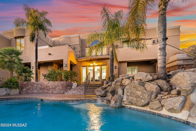 pool at dusk with french doors and pool water feature