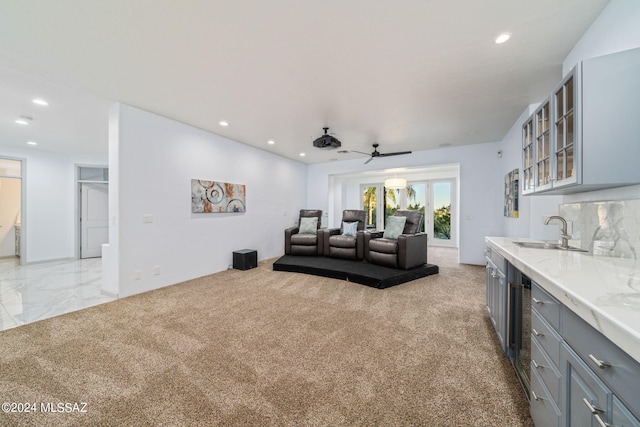 carpeted living room with wine cooler, ceiling fan, and sink