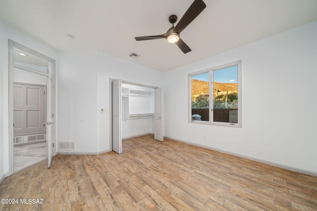 unfurnished bedroom with light wood-type flooring, ceiling fan, and a closet