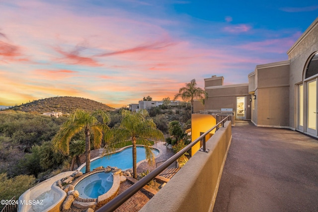 balcony at dusk with a mountain view and an in ground hot tub