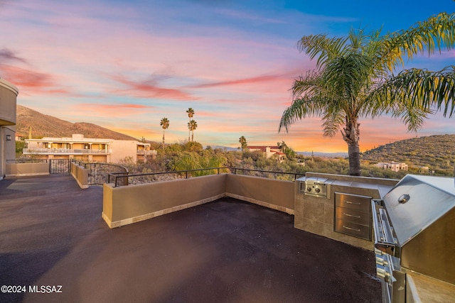 patio terrace at dusk with a mountain view, area for grilling, and a grill