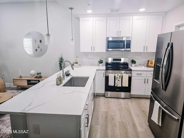 kitchen featuring white cabinets, hanging light fixtures, sink, appliances with stainless steel finishes, and light stone countertops