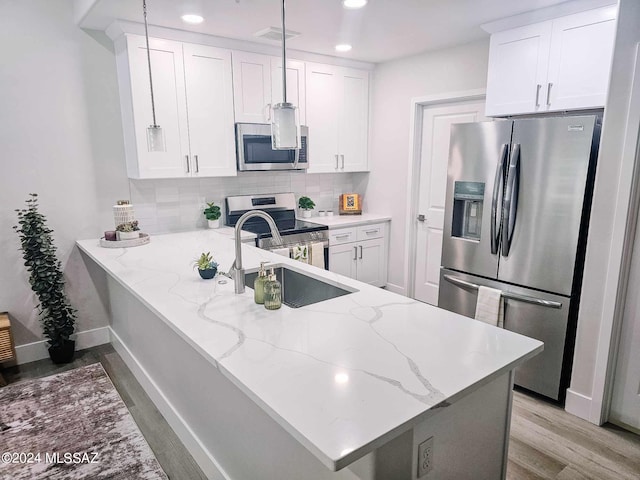 kitchen featuring white cabinets, appliances with stainless steel finishes, hanging light fixtures, and kitchen peninsula