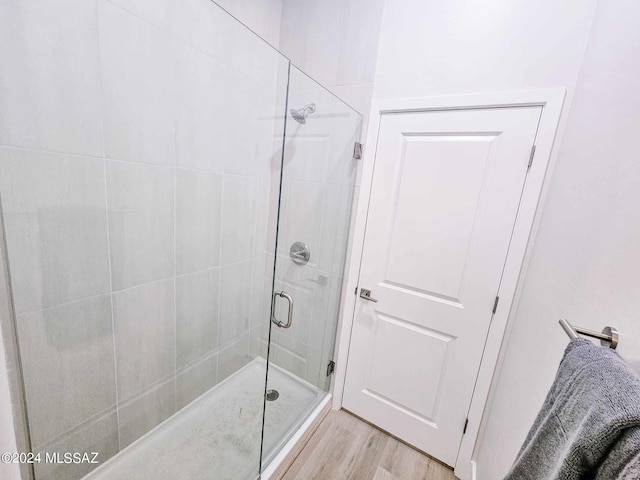 bathroom featuring hardwood / wood-style floors and a shower with shower door