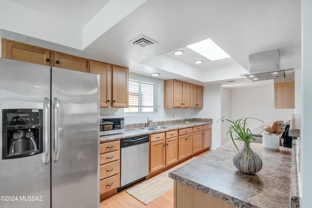 kitchen with appliances with stainless steel finishes, light brown cabinetry, sink, and light hardwood / wood-style floors