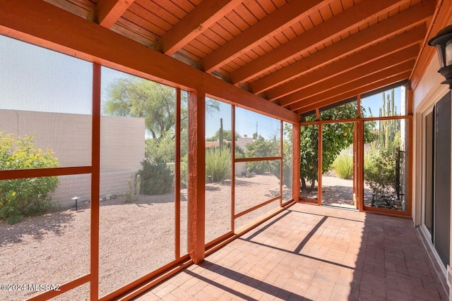 unfurnished sunroom featuring wood ceiling, vaulted ceiling with beams, and a wealth of natural light