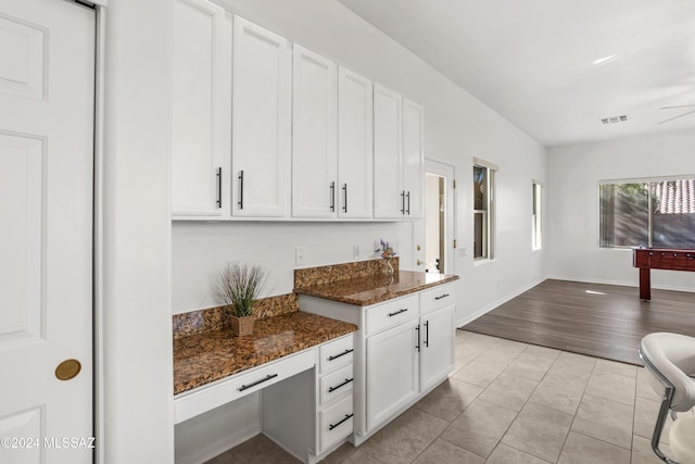 kitchen featuring light tile patterned flooring, white cabinets, and dark stone counters