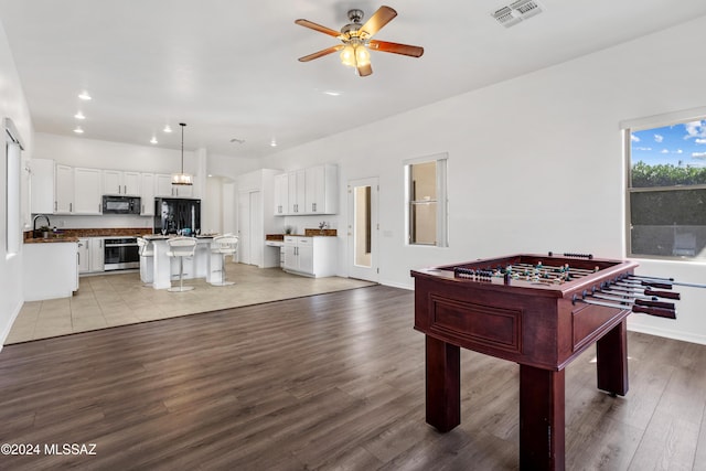 rec room with ceiling fan, sink, and light wood-type flooring