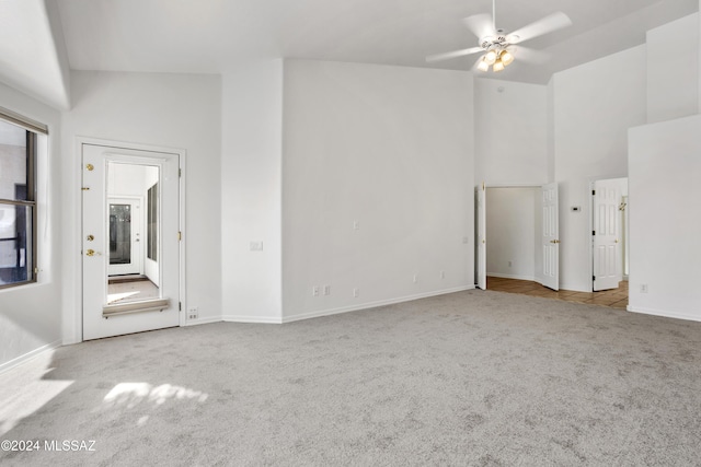 carpeted spare room with ceiling fan and high vaulted ceiling