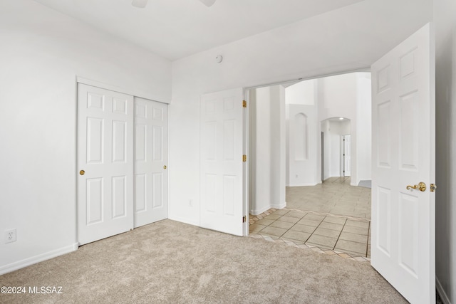 unfurnished bedroom with light carpet, a closet, and ceiling fan