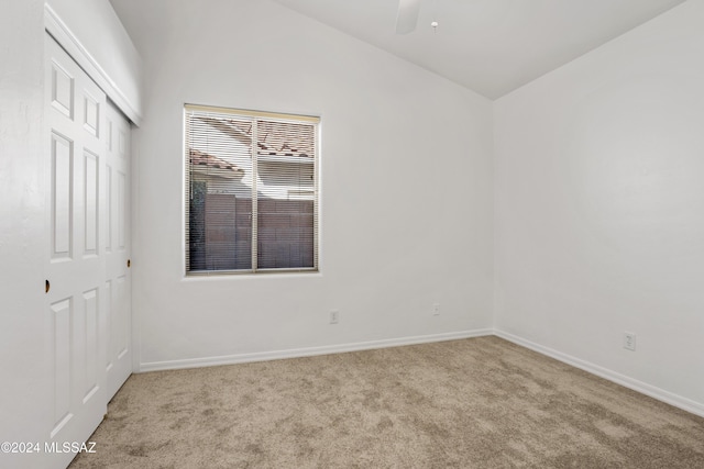 carpeted empty room featuring vaulted ceiling and ceiling fan