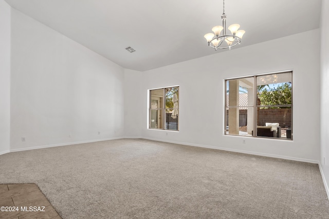 spare room with carpet floors and a notable chandelier