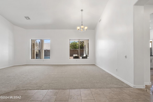 carpeted empty room with high vaulted ceiling and an inviting chandelier