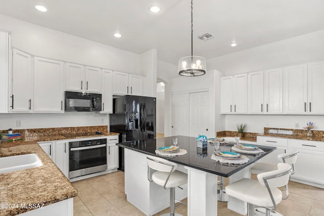 kitchen with pendant lighting, white cabinetry, a kitchen breakfast bar, black appliances, and a kitchen island