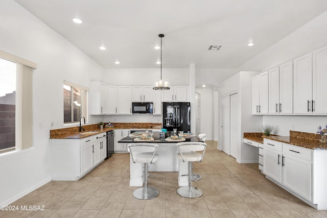 kitchen featuring hanging light fixtures, black appliances, white cabinets, and a kitchen island