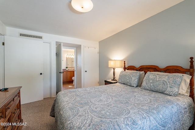 bedroom with ensuite bathroom and carpet floors