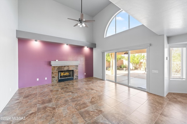 unfurnished living room featuring a healthy amount of sunlight, a fireplace, ceiling fan, and high vaulted ceiling