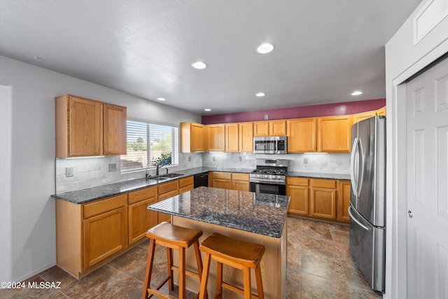 kitchen with dark stone countertops, a breakfast bar, a kitchen island, stainless steel appliances, and sink