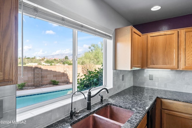 kitchen with dark stone counters, a wealth of natural light, and sink