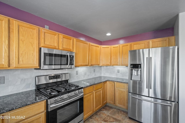 kitchen featuring decorative backsplash, dark stone countertops, and appliances with stainless steel finishes