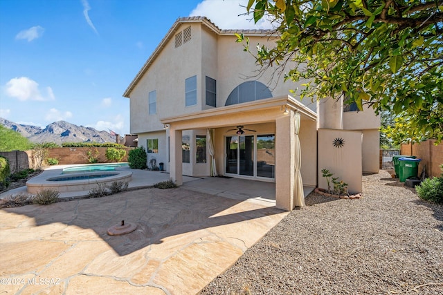 back of house with a mountain view, ceiling fan, an in ground hot tub, and a patio area