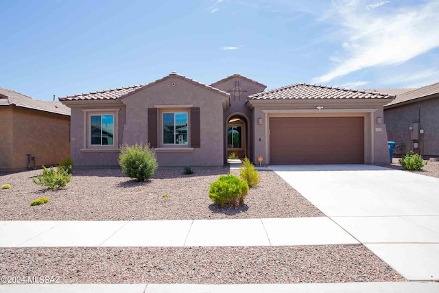view of front of home featuring stucco siding, a tile roof, driveway, and a garage