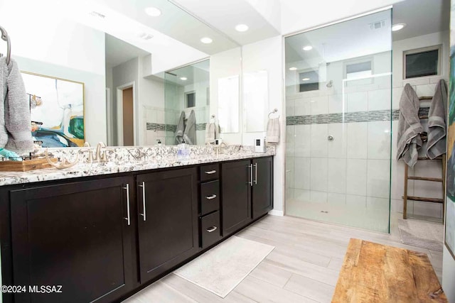 bathroom with a shower stall, a sink, double vanity, and recessed lighting