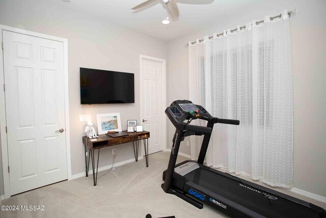 workout room with ceiling fan and light colored carpet