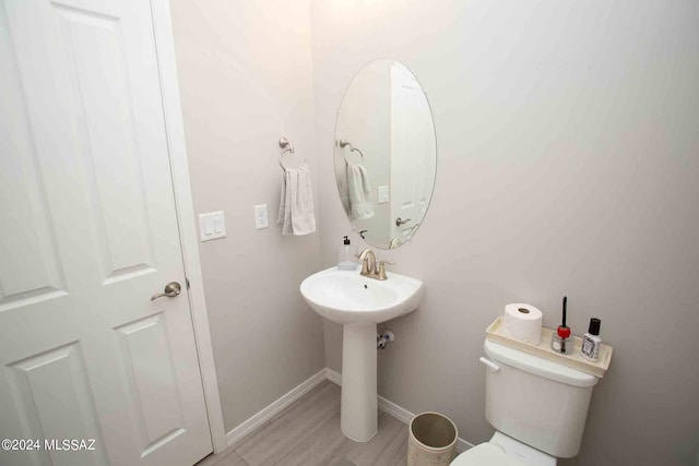 half bath with baseboards and toilet