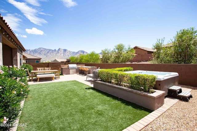 view of yard featuring a patio area, a fenced backyard, a mountain view, a hot tub, and an outdoor kitchen